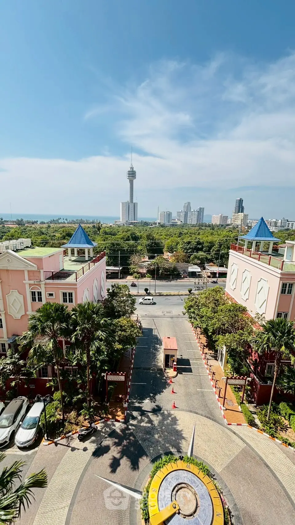 Stunning cityscape view from a high-rise balcony overlooking lush greenery and urban skyline.