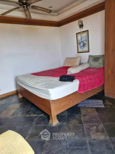 Cozy bedroom with wooden bed frame and stone tile flooring, perfect for relaxation.