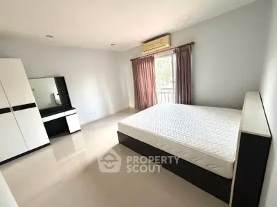 Spacious bedroom with modern furniture and natural light, featuring a large bed and balcony access.