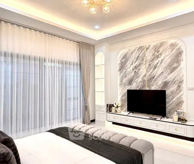 Luxurious bedroom with elegant decor and modern entertainment setup.