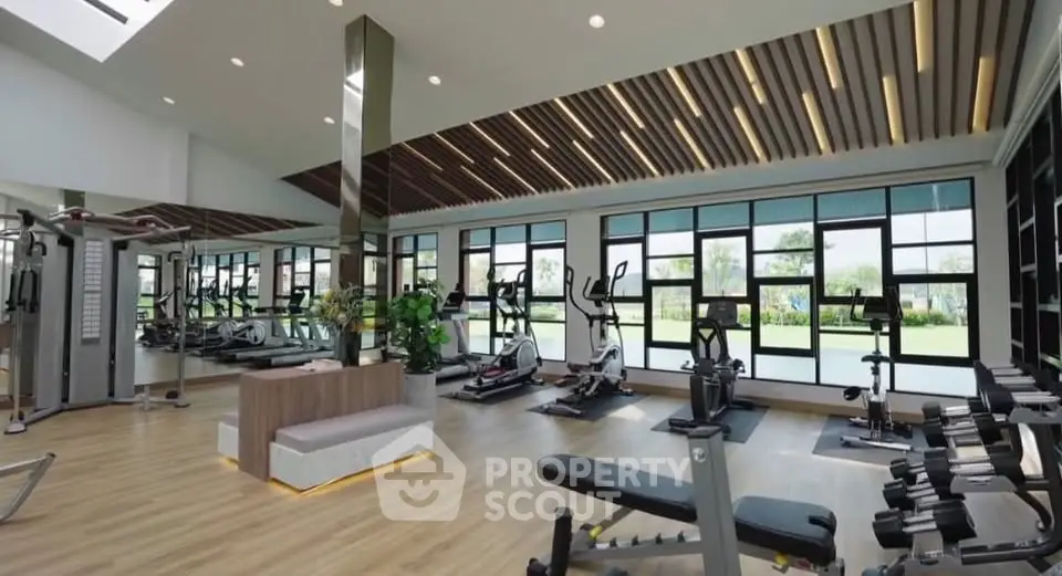 Spacious modern gym with state-of-the-art equipment and large windows offering scenic views.