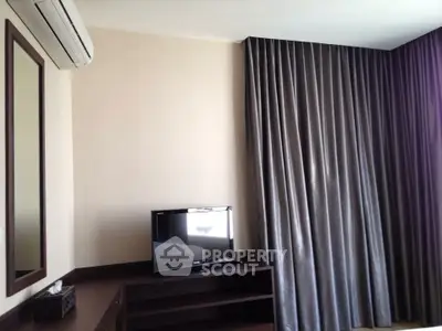 Modern living room with TV, air conditioning, and elegant curtains.