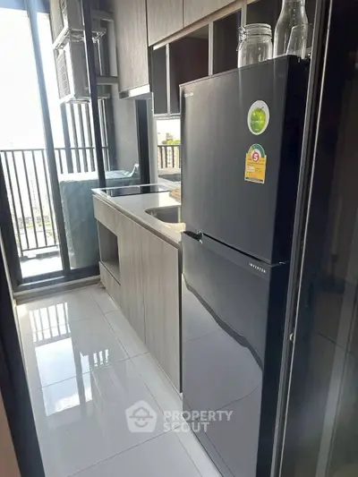 Modern kitchen with sleek black fridge and balcony view