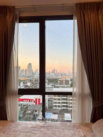 Stunning cityscape view from a cozy bedroom window at sunset.