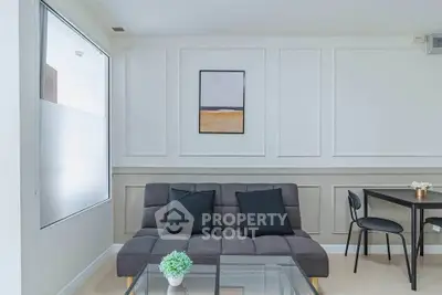 Modern living room with stylish sofa and glass coffee table in bright interior.