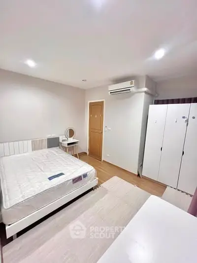 Spacious bedroom with modern furnishings and ample storage in a well-lit apartment.