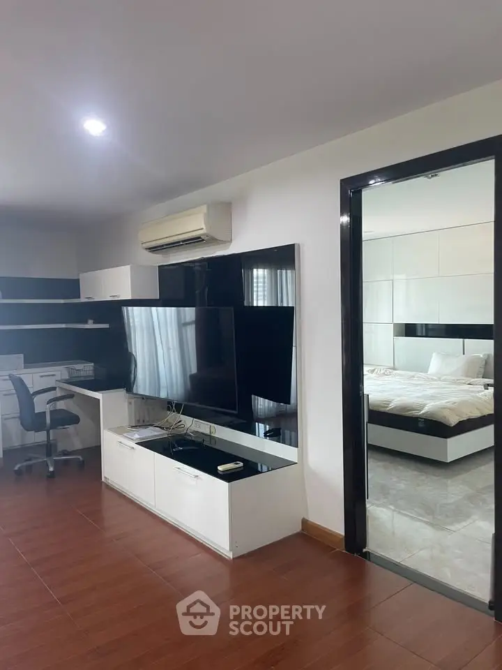 Modern living room with sleek furniture and a glimpse into a cozy bedroom, perfect for urban living.