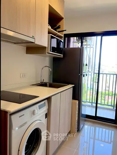 Modern kitchen with washing machine and balcony view in compact apartment