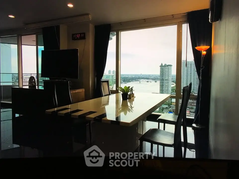 Luxurious living room with stunning river view and modern decor in high-rise apartment.
