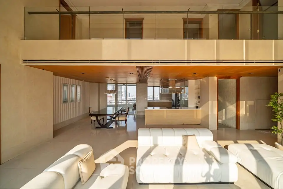 Luxurious modern living room with open kitchen and elegant furnishings, featuring large windows and abundant natural light.