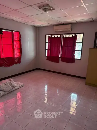 Spacious empty room with tiled flooring and red curtains, ideal for customization.
