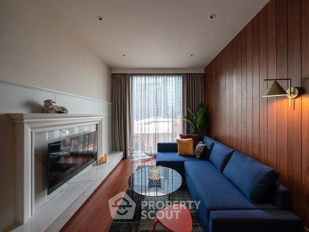 Modern living room with blue sectional sofa, fireplace, and large window with city view.