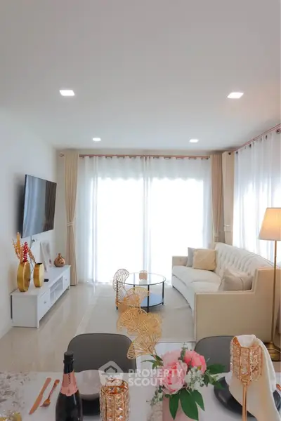 Elegant living room with modern decor and natural light, featuring a cozy sofa and stylish dining setup.