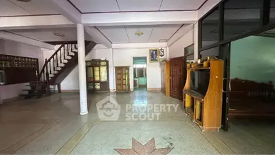 Spacious living room with unique flooring and wooden staircase in a residential property.