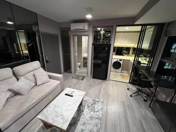 Modern living room with sleek furniture and integrated kitchen appliances in a stylish apartment.