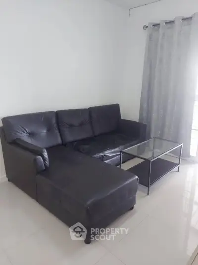 Modern living room with sleek black leather sofa and glass coffee table