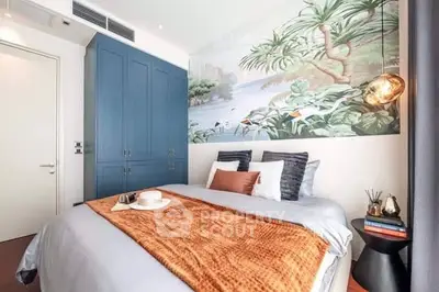 Stylish bedroom with mural and blue wardrobe, cozy and inviting decor.