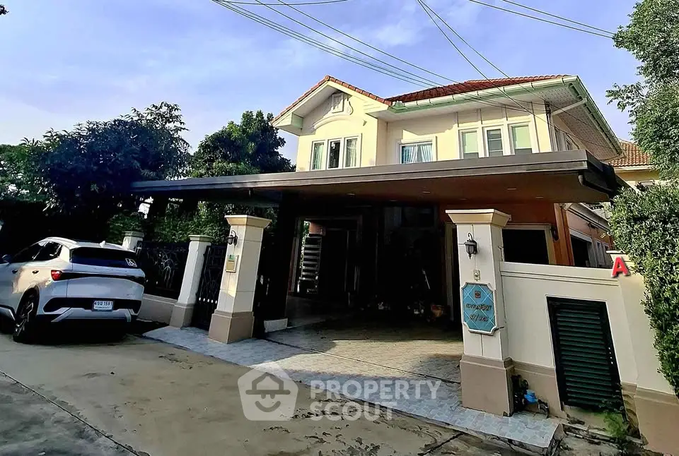 Charming two-story house with carport and lush greenery in a serene neighborhood.