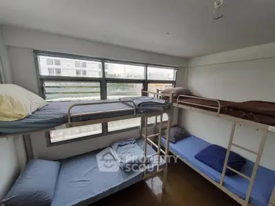 Spacious dormitory room with four bunk beds and large windows offering natural light.