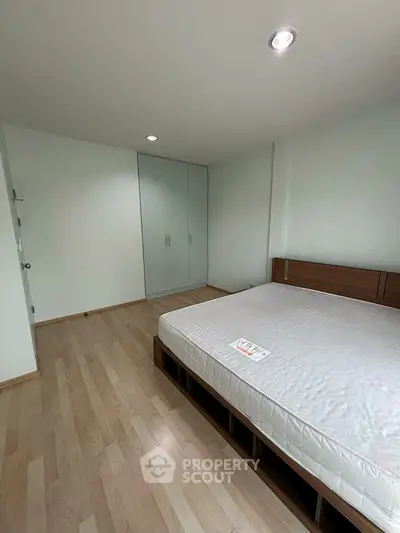 Spacious bedroom with wooden flooring and built-in wardrobe, perfect for modern living.