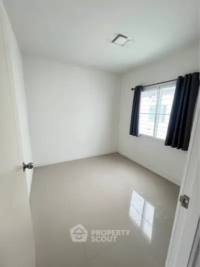 Spacious empty bedroom with large window and tiled floor, ready for customization.