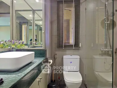 Modern bathroom with sleek design, featuring a stylish sink, toilet, and shower area with elegant finishes.