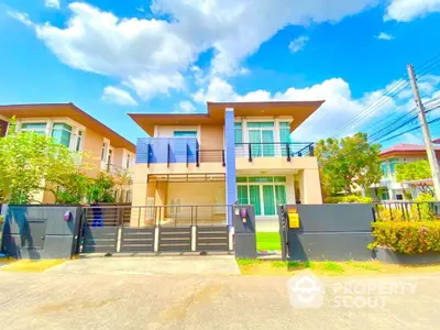 Modern two-story house with sleek design and spacious front yard under a clear blue sky.