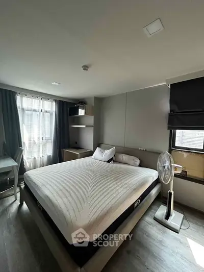 Modern bedroom with stylish decor and natural light, featuring a comfortable bed and sleek furnishings.