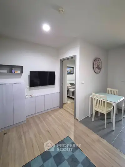 Modern living room with TV, dining area, and view into bedroom