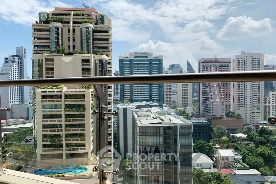 Stunning cityscape view from a high-rise balcony with modern buildings and clear blue sky.