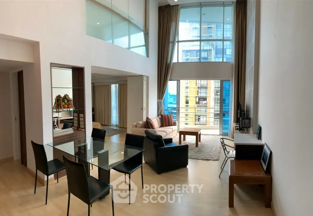 Spacious modern living room with high ceilings and large windows offering city views.