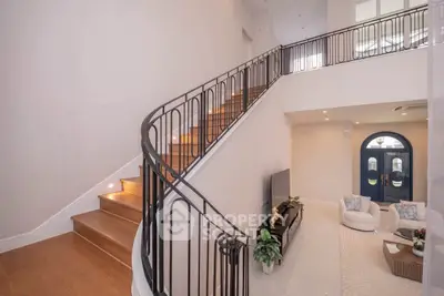 Elegant living room with curved staircase and modern decor in a spacious home.