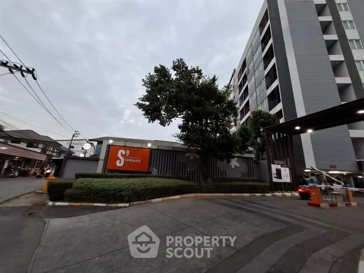 Modern apartment building exterior with gated entrance and lush greenery.