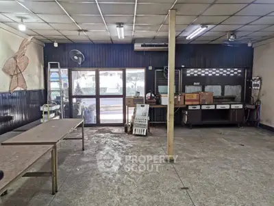 Spacious industrial-style room with large windows and metal tables, ideal for workshop or creative space.