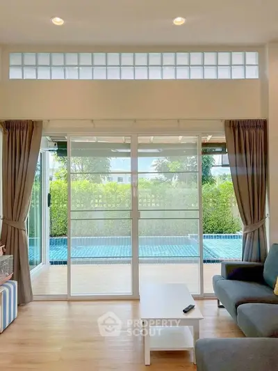 Spacious living room with pool view and sliding glass doors, perfect for relaxation and entertainment.