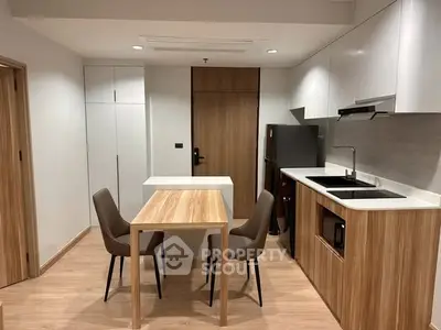 Modern kitchen with sleek wooden cabinetry and dining area in a stylish apartment.