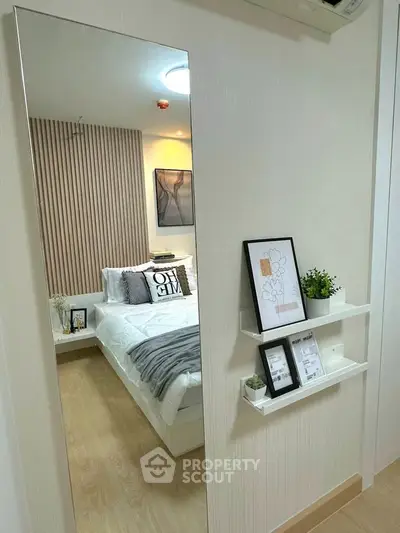 Modern bedroom with stylish decor and cozy ambiance, featuring a large mirror and elegant wall art.