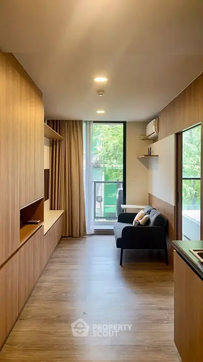 Modern living room with wooden flooring, cozy sofa, and large window with balcony view.