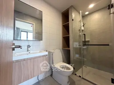 Modern bathroom with glass shower and wooden vanity in stylish apartment.