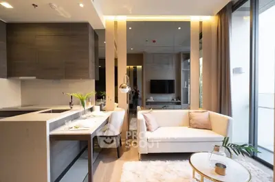 Modern open-layout living room with stylish kitchen and cozy seating area, featuring elegant decor and natural light.