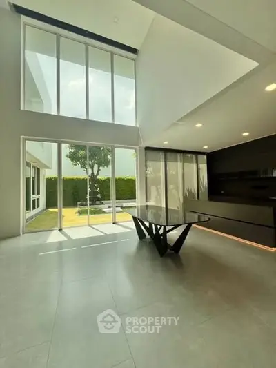 Spacious modern living room with high ceilings and large windows overlooking garden