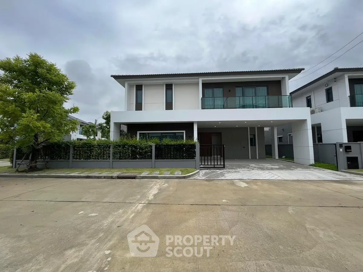 Modern two-story house with spacious driveway and lush greenery in a serene neighborhood.
