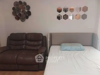 Cozy living room with sofa and bed, modern wall decor, ideal for compact living spaces.