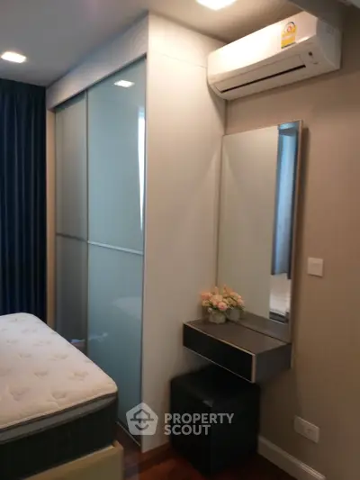Modern bedroom with sleek wardrobe and air conditioning unit, featuring a cozy vanity area.