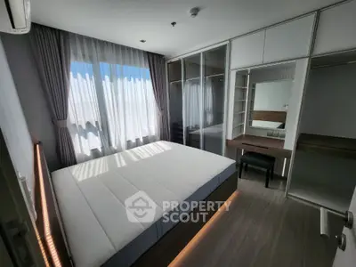 Modern bedroom with large window and built-in wardrobe in stylish apartment.