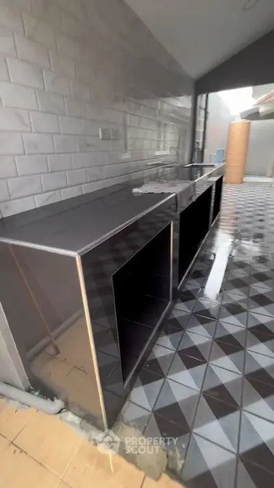 Modern kitchen with sleek stainless steel countertops and geometric tile flooring