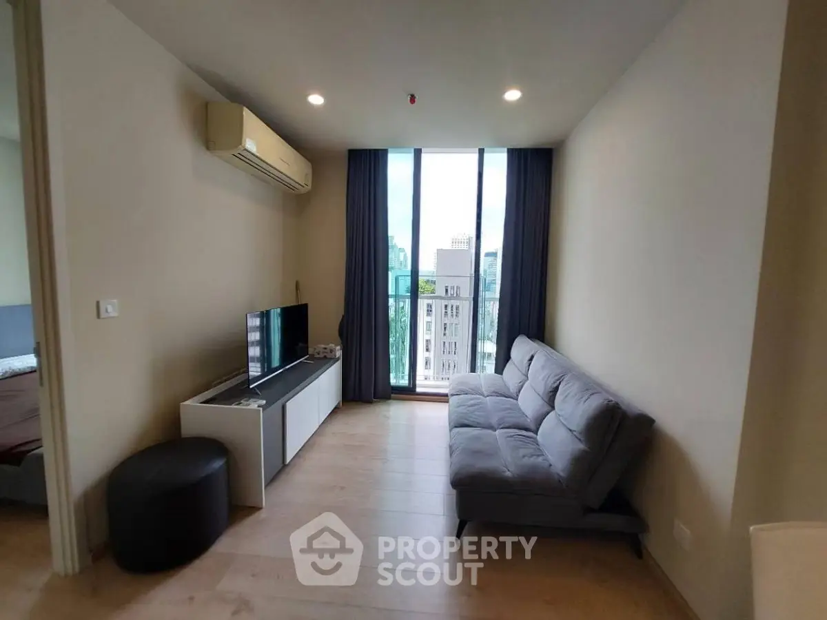 Modern living room with large window and city view, featuring a sleek sofa and entertainment unit.