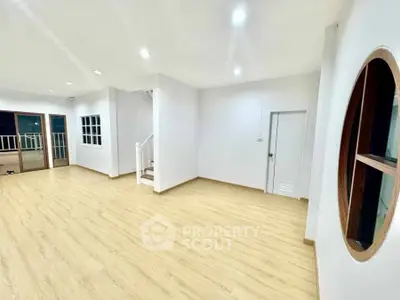 Spacious modern living room with wooden flooring and unique round window.