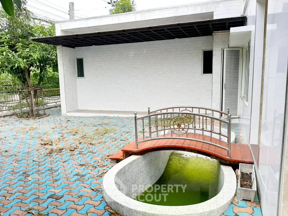 Charming exterior with small bridge over decorative pond and tiled patio area.