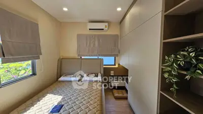 Cozy bedroom with modern design, featuring built-in storage and natural light.